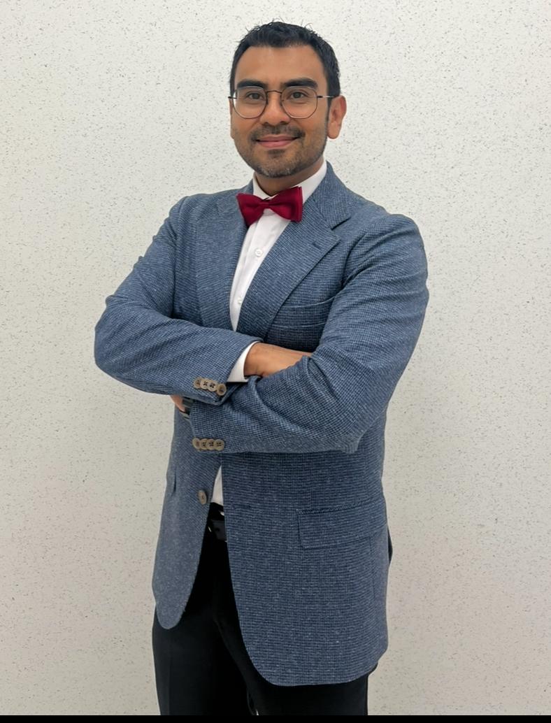 Doctor Miguel Bernés Neurocirujano en CDMX posando para fotografía afuera de hospital con saco y corbatín rojo